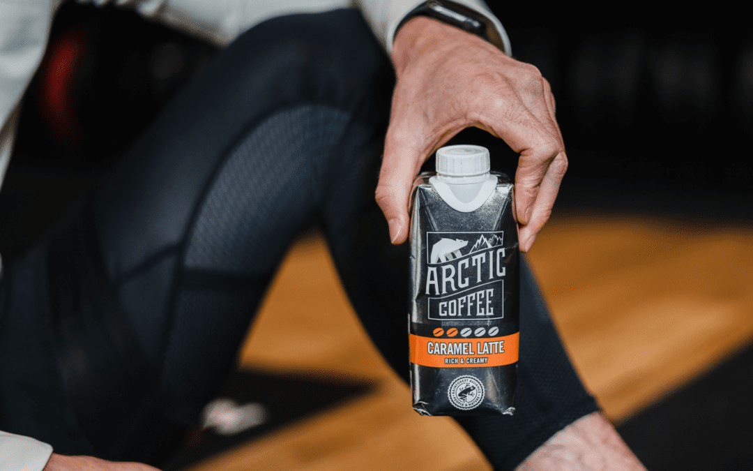 A gym goer holding a carton of Arctic Iced Coffee