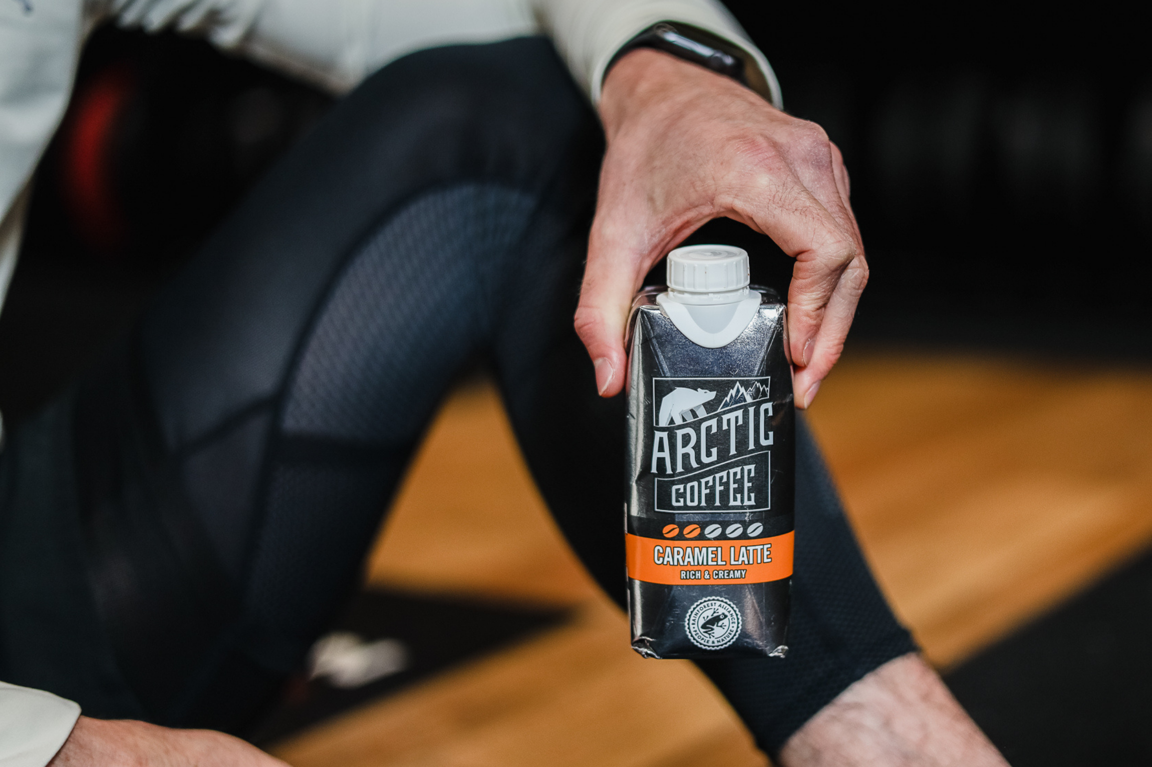 A gym goer holding a carton of Arctic Iced Coffee